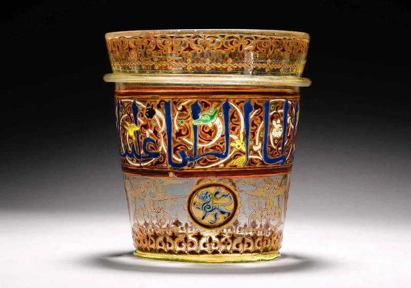 Lampu Masjid Berlapis Emas dari Era Mamluk, Abad ke-14. Salah satu artefak ikonik dalam lelang Arts of the Islamic World & India di Sotheby’s London, lampu kaca ini merupakan peninggalan Kesultanan Mamluk di Mesir. Dihiasi kaligrafi kufi dan motif arabes, benda ini dulunya menggantung di langit-langit masjid, melambangkan cahaya Ilahi. Karya ini mencerminkan puncak kejayaan seni Islam pada masa Mamluk, ketika keindahan dan spiritualitas berpadu dalam bentuk yang fungsional dan artistik. Credit: Sotheby's.