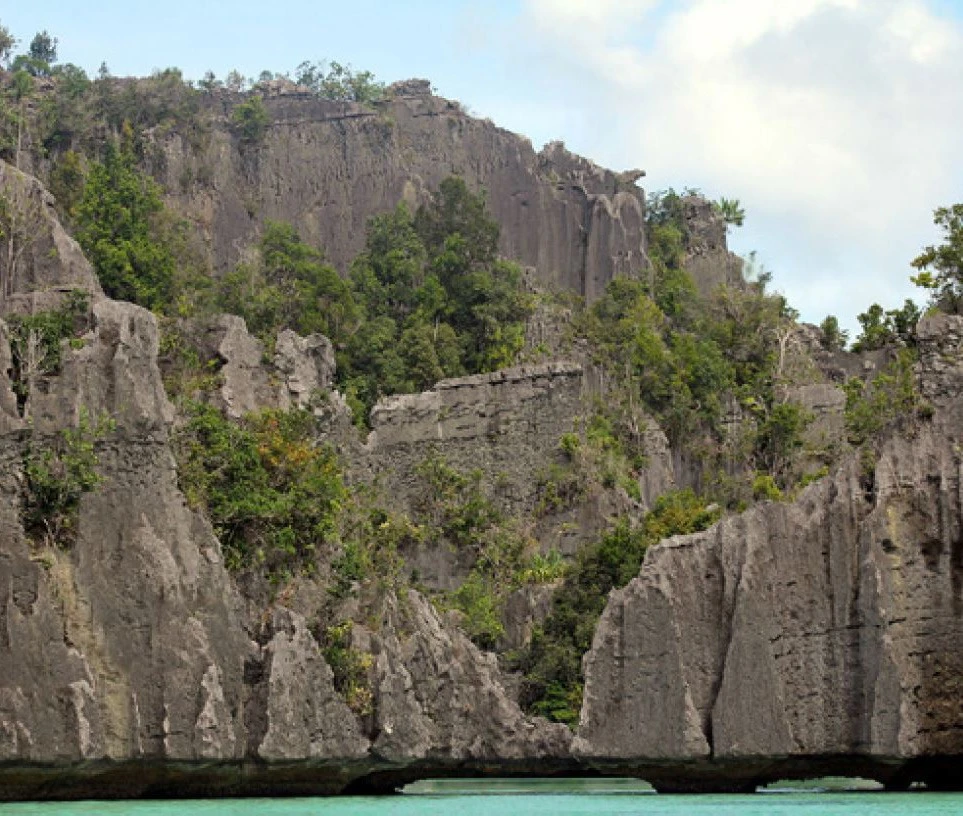 Tebing-tebing karst yang menjulang di perairan jernih Raja Ampat ini bukan hanya menyimpan keindahan geologis, tetapi juga kisah purba tentang bumi Papua yang megah dan lestari. Kredit: Raja Ampat Geopark.