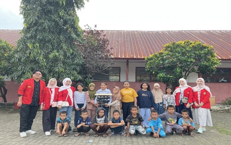 Mahasiswa Posko 22 FKM Unhas berfoto bersama siswa-siswi SDN 10 Bangkala usai kegiatan evaluasi pelatihan pembuatan ecobrick. Di tengah mereka tampak hasil karya ecobrick yang berhasil dirakit menjadi meja. Kredit: FKM Unhas.