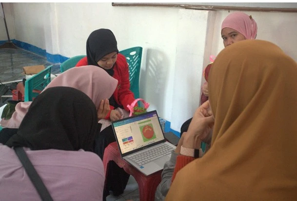 Mahasiswa FKM Unhas membimbing warga Dusun Ballapati dalam simulasi desain logo dan kemasan produk dari sampah, sebagai bagian dari program JUARA 
