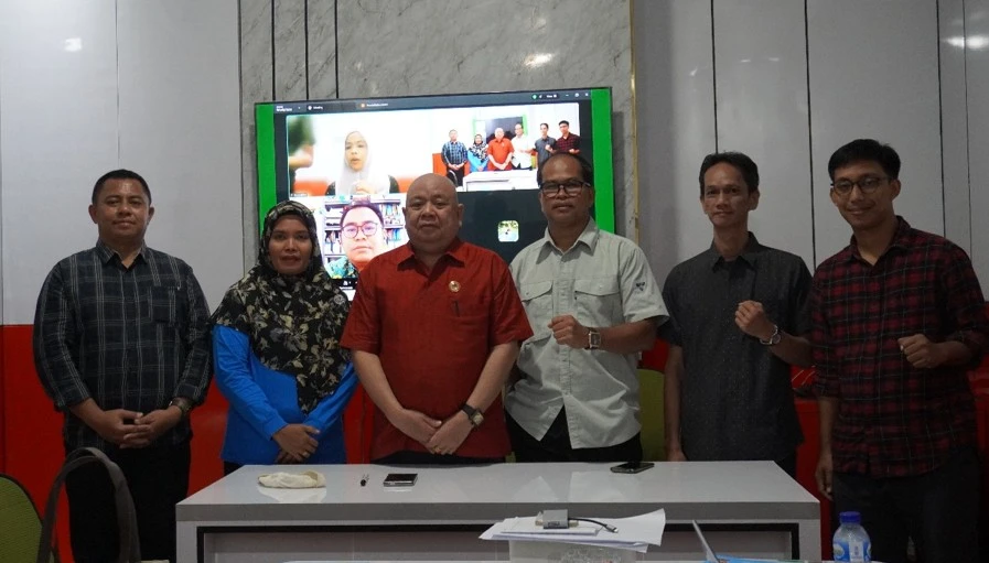 Kepala PSLH LPPM Unhas, Prof. Dr. Anwar Daud, SKM., M.Kes. (tengah), bersama panitia dan peserta luring Pelatihan Penilai AMDAL yang berlangsung 1–8 November 2025, berfoto bersama di ruang pelatihan Unhas. Peserta lain dari Donggala, Samarinda, dan individu profesional turut bergabung secara daring melalui layar konferensi di belakang.