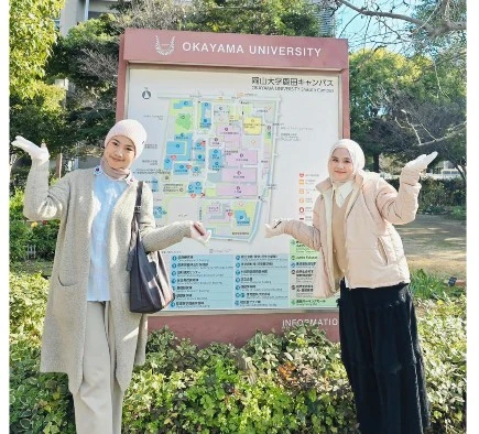Dua mahasiswi Unhas berpose di depan peta kampus Okayama University, Jepang, saat mengikuti Program Student Exchange for Undergraduate pada 13–19 Desember. Program ini menjadi bagian dari penguatan pengalaman akademik internasional dan pembelajaran lintas budaya mahasiswa Unhas.