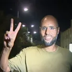 Saif al-Islam Gaddafi, putra mantan pemimpin Libya Muammar Gaddafi, memberikan tanda 'V' di Tripoli pada 23 Agustus 2011 (Kredit: Reuters).